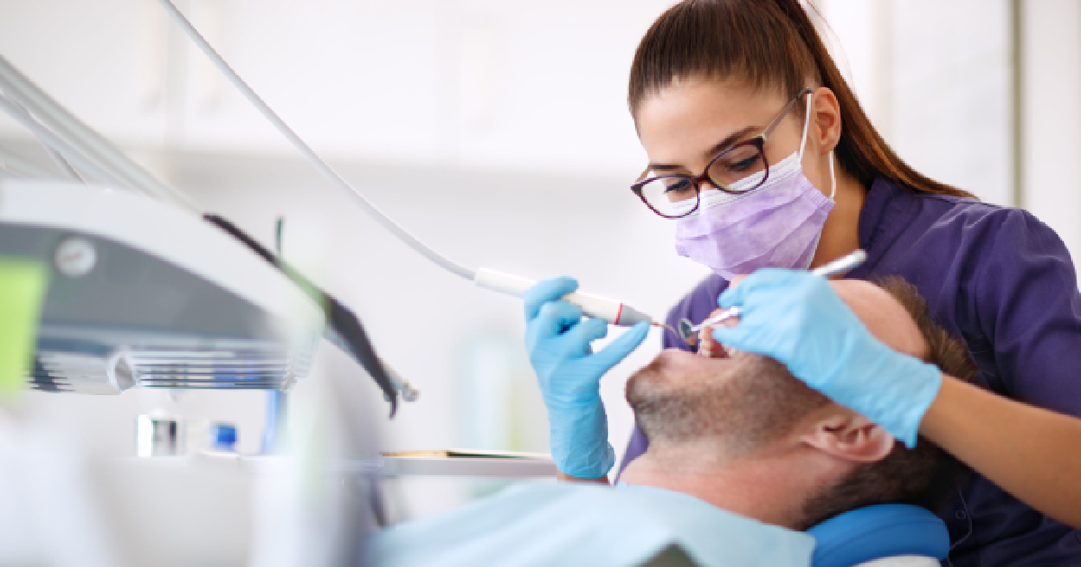 Dentist treating a male patient for traumatic dental injuries in Summerville, SC, using professional dental tools