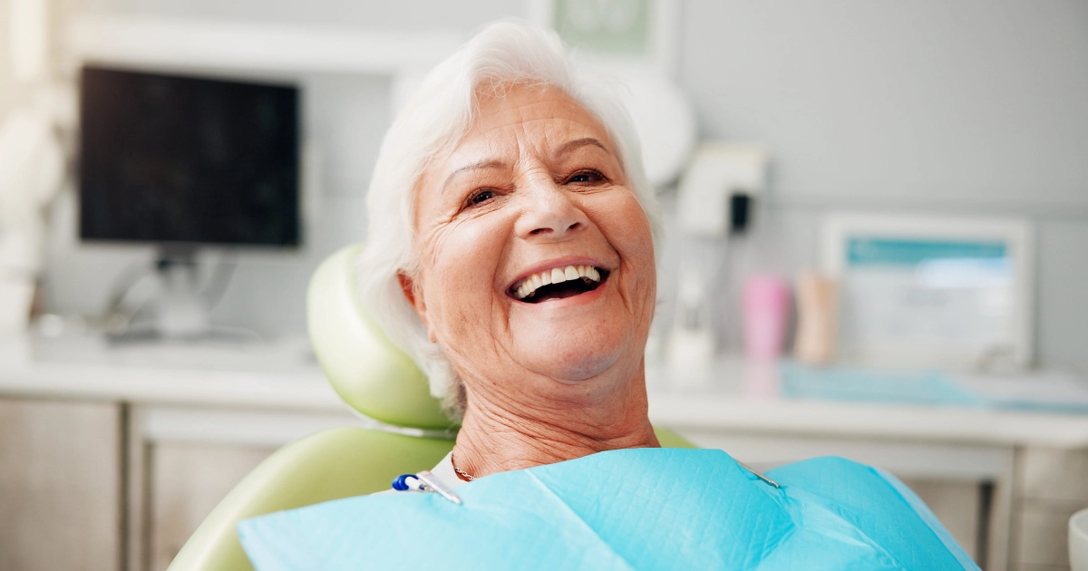 A happy senior woman with a bright smile sitting in a dental chair after her GentleWave Procedure in Summerville, SC.